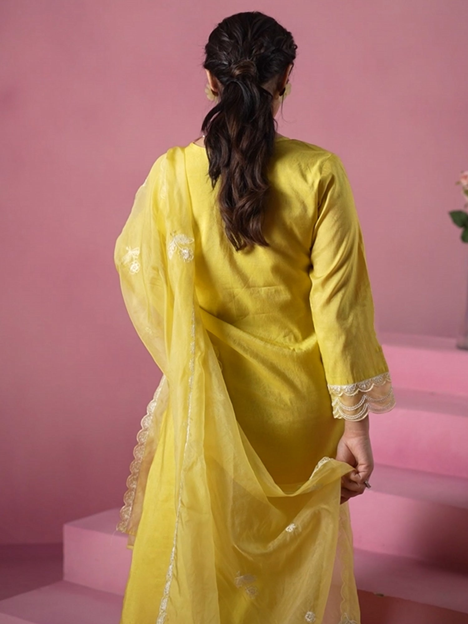Women wearing a yellow traditional outfit with a pink background