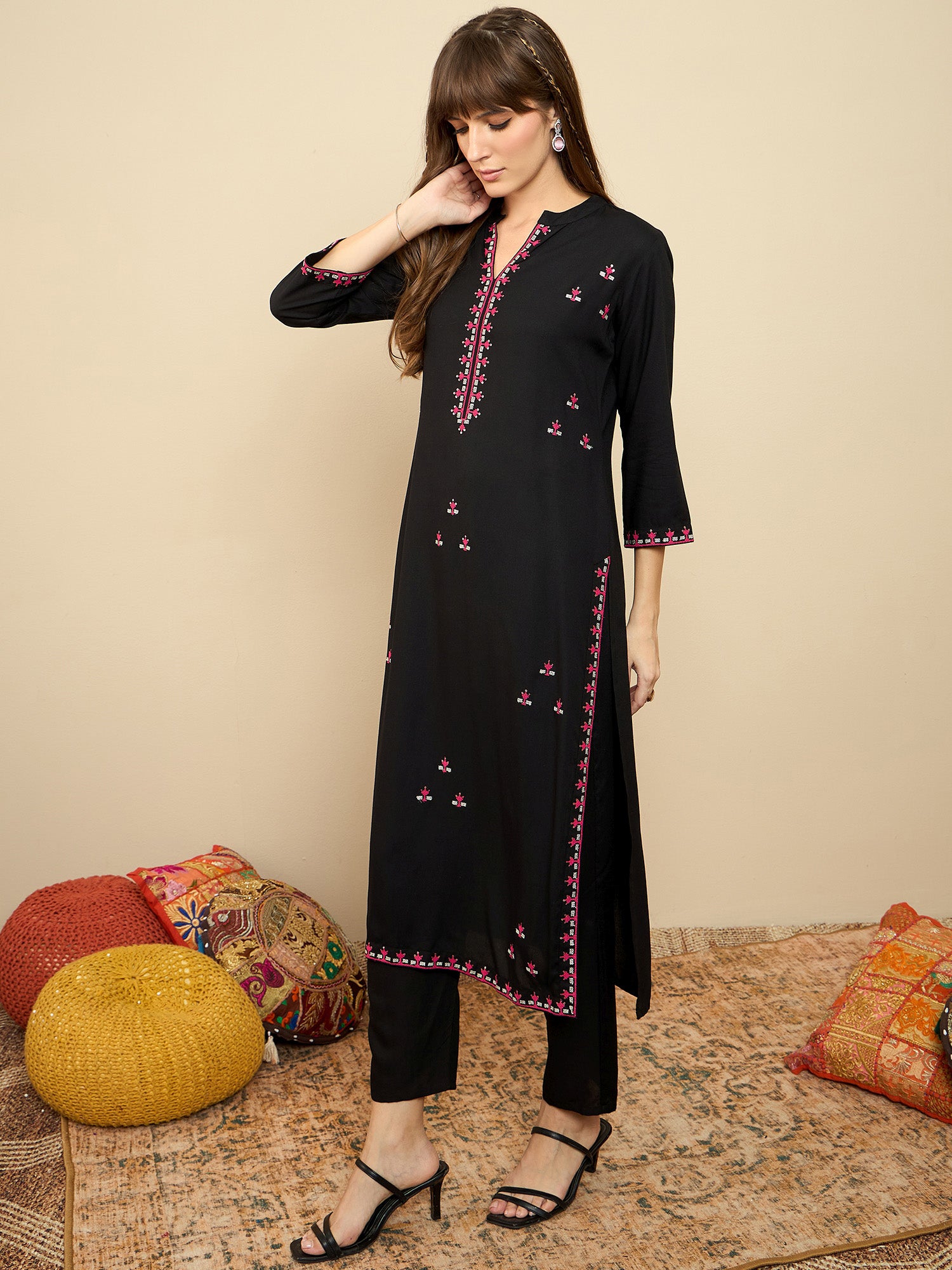 Woman wearing a black embroidered kurta with pants on a beige background