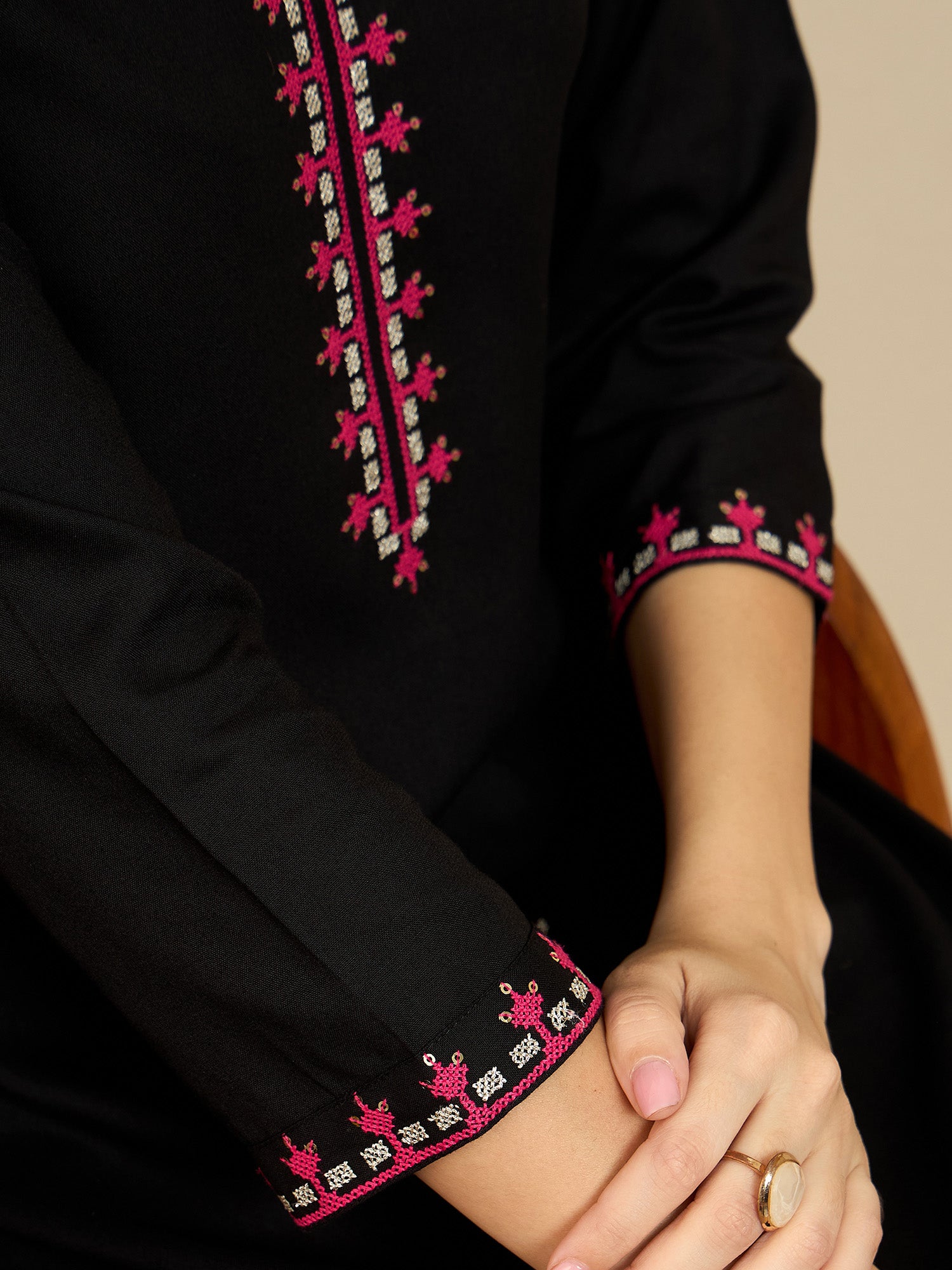 Black garment with pink and white embroidery on a neutral background