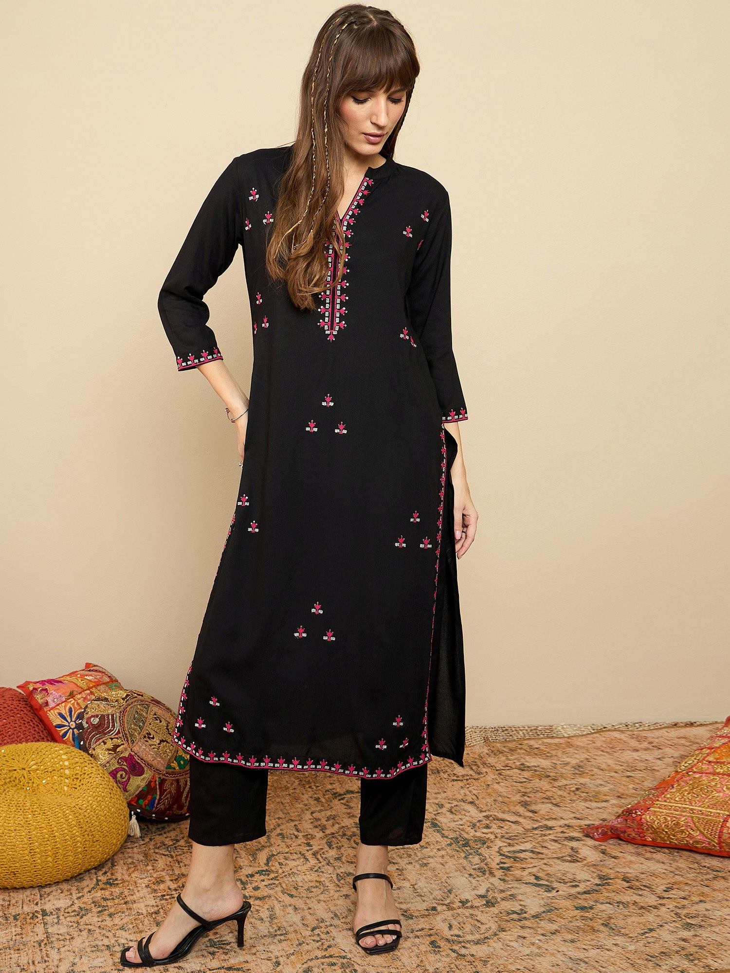 Woman wearing a black embroidered kurta with pants on a beige background